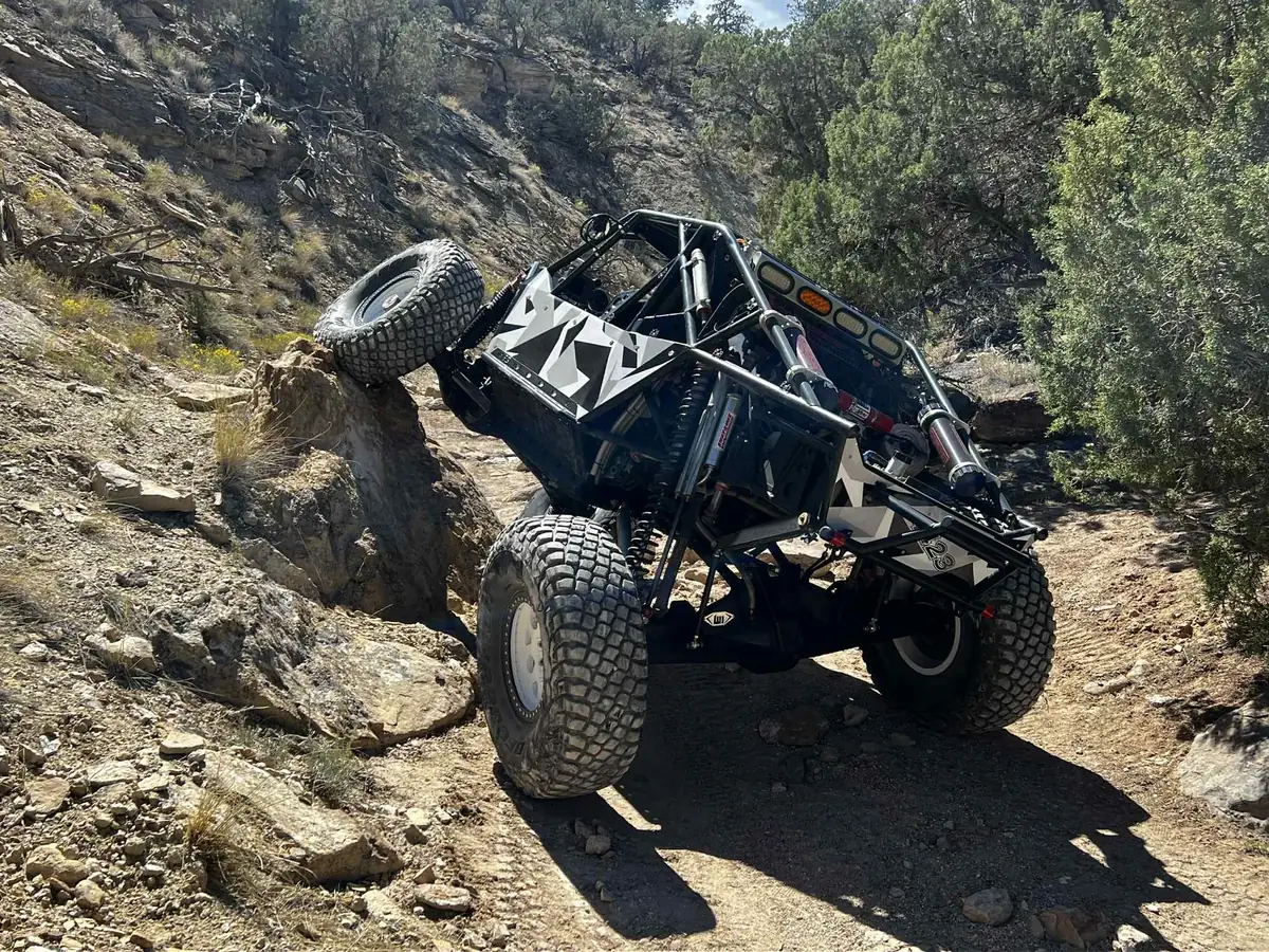 Black-and-white TCOR buggy navigating a rocky trail